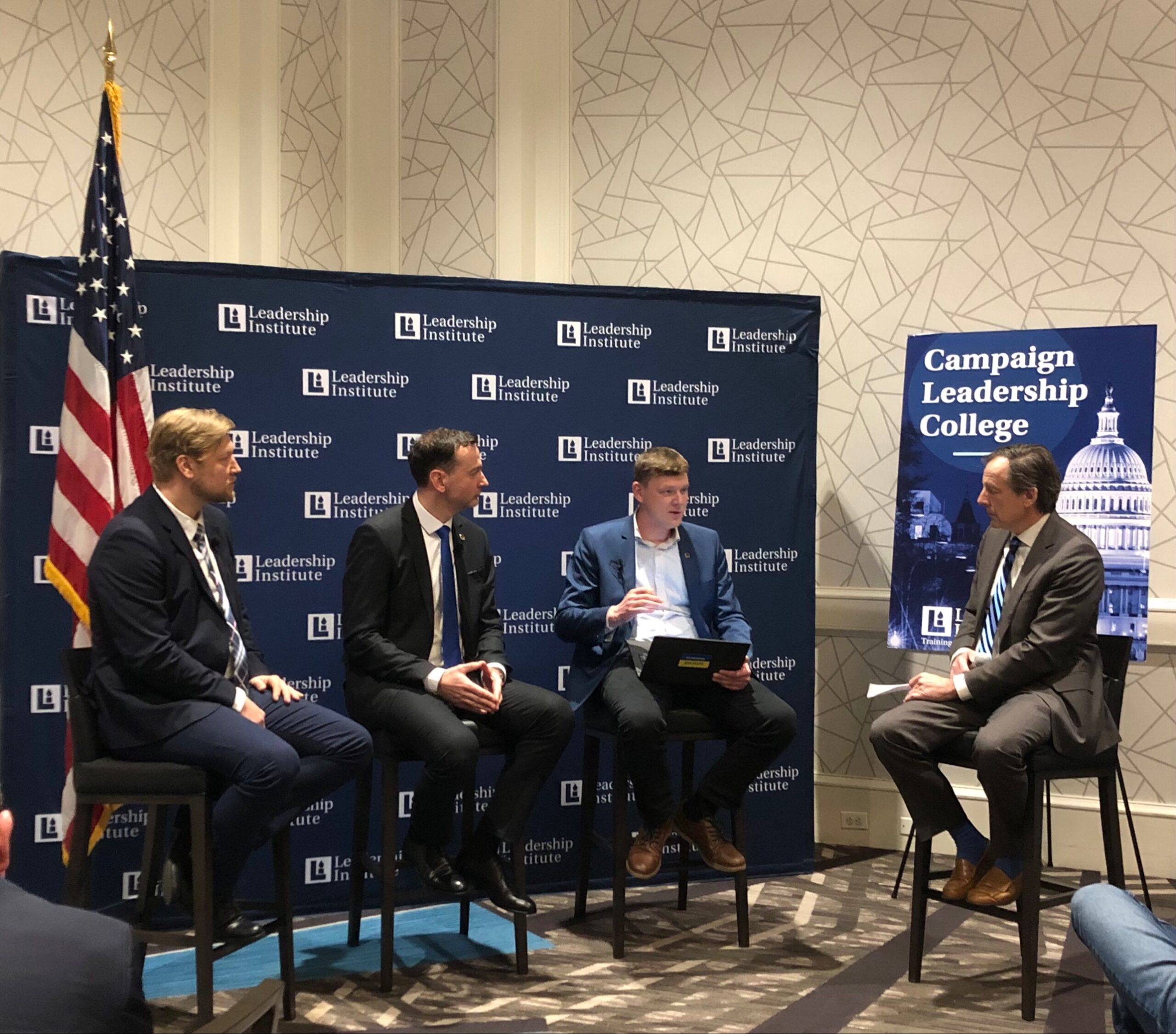 Four men participate in a panel discussion at a Leadership Institute Campaign Leadership College training event, seated in front of LI branded backdrop with American flag visible.